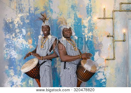 A Group Of People In Traditional African Costumes Playing Jembe Drums