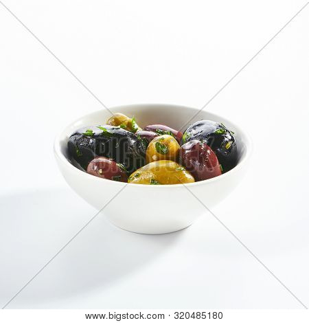 Delicious olive assorti marinated in oil closeup. Mediterranean cuisine restaurant dish, menu item. Tasty greek snack, appetizer isolated on white background. Organic food, natural vegetarian meal