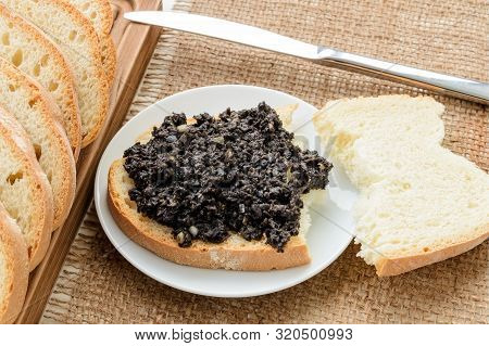 Tapenade Sandwich On A Sauser, Table Knife And Sliced Wheat Bread On A Burlap Table Napkin. Homemade