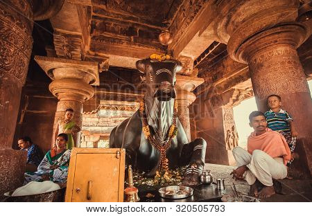 Pattadakal, India: Hindu People Sitting Near Nandi Bull After Puja Ritual In Traditional Temple On F