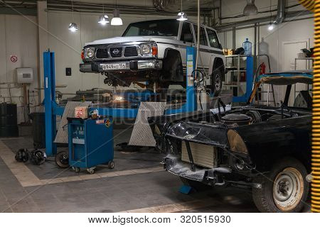 Novosibirsk, Russia - 08.01.2018: White Used Car Nissan Patrol Raised On A Blue Lift For Repairing T