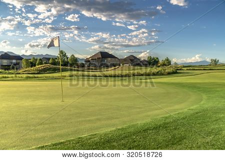 Flagstick On The Fairway Of A Golf Course With Houses In The Background