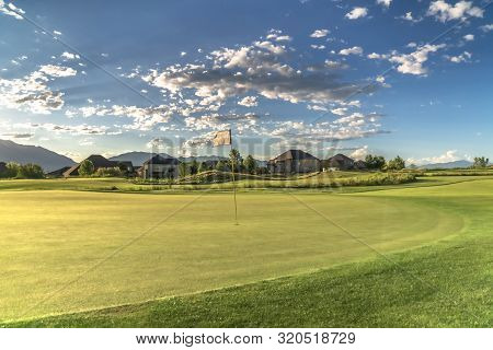 Golf Course With A Flagstick In The Middle Of The Fairway Under Cloudy Blue Sky