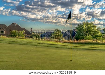 Flagstick Hole And Fairway Of A Golf Course With Homes And Trees Background