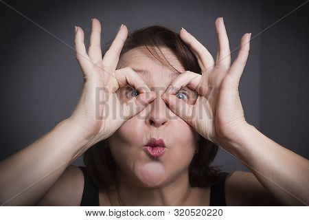 Woman Grimaces In Front Of Camera On Black Background