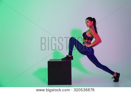 Photo of amazing beautiful young sports woman posing isolated with led flash lights make stretching exercises.
