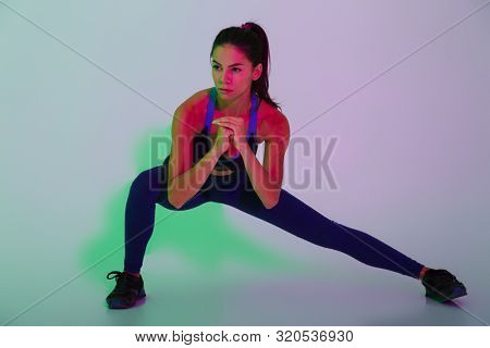 Image of pretty young sports woman posing isolated with led flash lights make stretching exercises.
