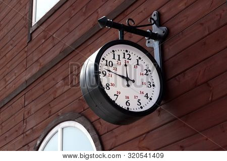 Vintage Vintage Clock With A Round Dial Hang On A Wooden Wall At The Railway Station. Reconstruction