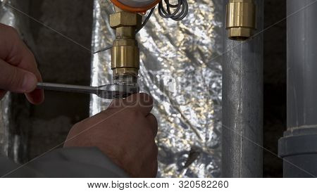 Plumber Unscrews A Wrench Unscrews A Nut On A Water Pipe