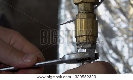Plumber Unscrews A Wrench Unscrews A Nut On A Water Pipe