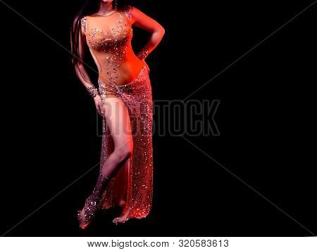 The Body Of A Beautiful Girl In A Beaded Suit For Belly Dancing On A Black Background. Sexy Woman In