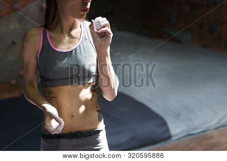 Athletic Muscular Woman With Muscular Naked Torso Getting Ready To Climbing. Woman Blowing Off Chalk