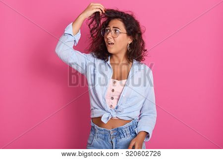 Portrait Of Young Beautiful Woman With Dark Wavy Hair, Touches Her Curl With Shocked Facial Expressi