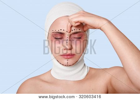 Close Up Portrait Of Beautiful Young Caucasian Woman Standing Against Blue Wall With Bandage On Head