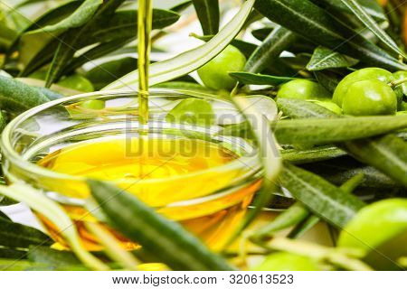 Olive Oil. Greek Freshly Squeezed Olive Oil Is Poured Into A Glass Transparent Bowl Among Olive Bran