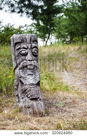 Wooden Idol Of Slavic God By A Path In The Forest. Forest In The Background.