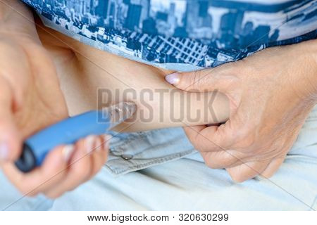 Elderly Woman Giving Herself Injection Against Osteoporosis In Abdomen.treating Diabetes In A People