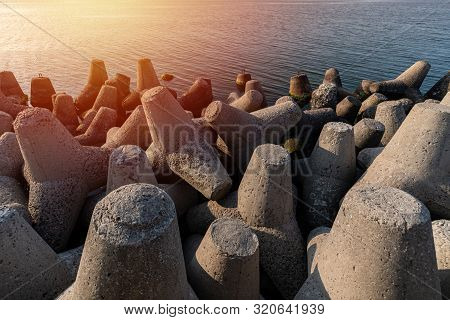 Tetrapod Breakwaters In Sea Water. Beautiful Sunset Seascape With Concrete Tetrapodes For Protect Co
