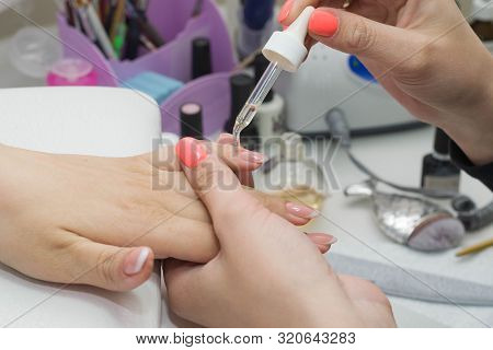 The Nail Technician Rubs The Oil On The Clients Hand.