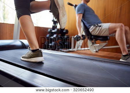 Detail Of Couple In Home Gym Exercising With Weights And Using Running Machine