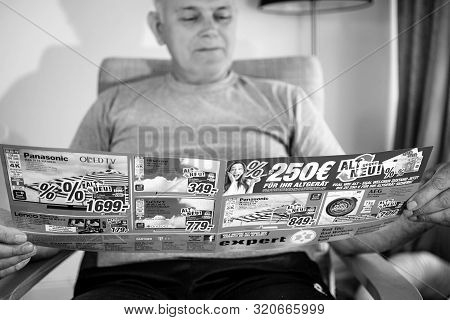 Paris, France - May 22, 2019: Senior Man Reading Wide Flyer Advertising Featuring On The Cover Multi