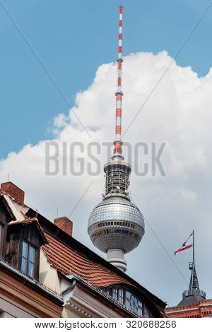 the Berliner Fernsehturm, the popular television tower of Berlin, Germany, highlighting above the tiled roofs of the houses of the Mitte district