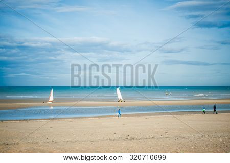 Two Sand Yachts Racing On The Beach On A Sunny Autumn Day Witt People Walking On The Beach