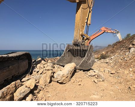 Excavators Moving A Rock Boulders During Road Construction On The Rocky Soils