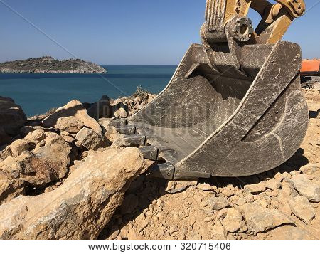 Excavator Scoop Moving A Rock Boulders During Road Construction On The Rocky Soils