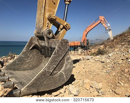 Excavator Scoop Moving A Rock Boulders During Road Construction On The Rocky Soils