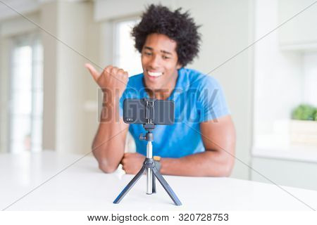 African American man doing online call with webcam using smartphone pointing and showing with thumb up to the side with happy face smiling