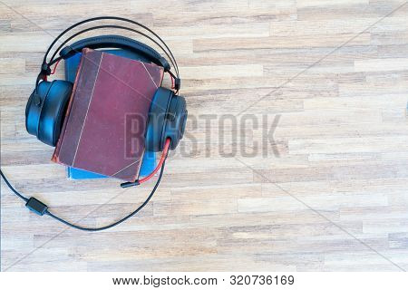 Audio Book Concept. Black Headphones And Books On Wooden Table. Top View With Copy Space.