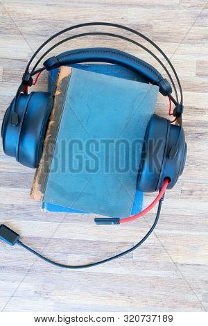 Audio Book Concept. Black Headphones And Pile Of Books On Wooden Table. Top View With Copy Space.