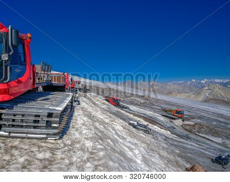 Special Caterpillar Equipment On The Slope Of Mount Elbrus Against The Backdrop Of A Mountain Range.
