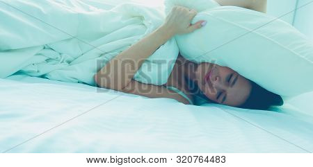 Young Caucasian Woman Covering Her Head And Ears With Pillows