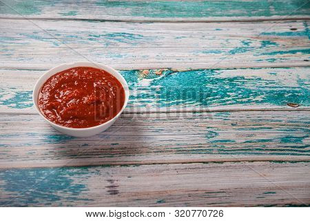 Harissa In A Cup On A Blue Wooden Background. Flat Lay. Iop View. Horizontal.