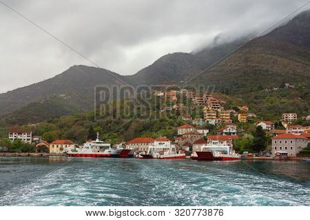 Picturesque Mediterranean Village On Mountainside Next To Ferry. Montenegro, Adriatic Sea, Bay Of Ko