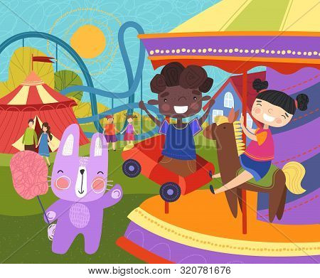 Two Young Children Having Fun At The Fairground Riding On A Colorful Carousel Or Merry-go-round Watc