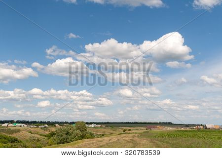 Beautiful White Clouds In The Blue Sky Over The Russian Village. Summer Afternoon Over A Russian Vil