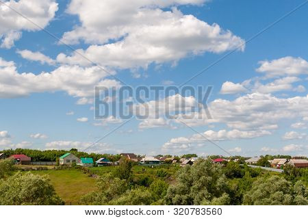 Beautiful White Clouds In The Blue Sky Over The Russian Village. Summer Afternoon Over A Russian Vil