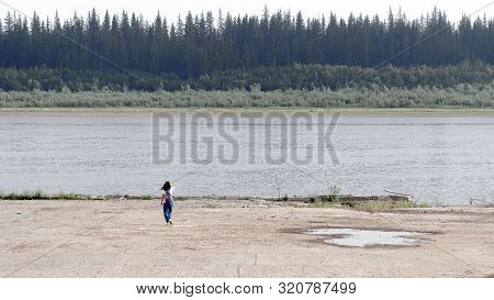 Tourist With Backpack Walking To The Edge Of The Concrete Touching The Hair On The Banks Of The Old 