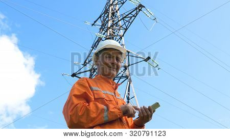 Surveyor In Jumpsuit And Helmet Smiles Holding Smartphone