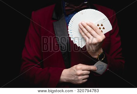 Illusionist Man Shows Fan Of Playing Cards Takes Ace Out Hand On Black Background