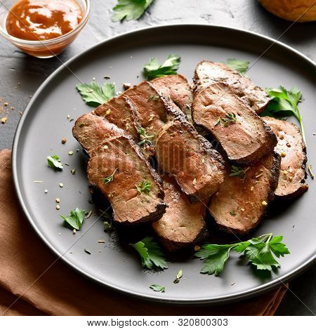 Close Up Of Grilled Sliced Beef Liver On Plate Over Black Stone Background. Cooked Liver(offal) From