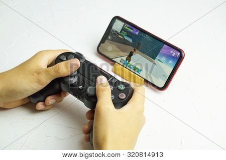 Bishkek, Kyrgyzstan - June 06, 2019: Man Playing Fortnite On Ios 13 With Sony Dualshock