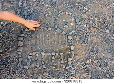 Child's Hand Stroking A Kitten's Mosaic Puzzle Laid Out On A Gray Surface By A Child