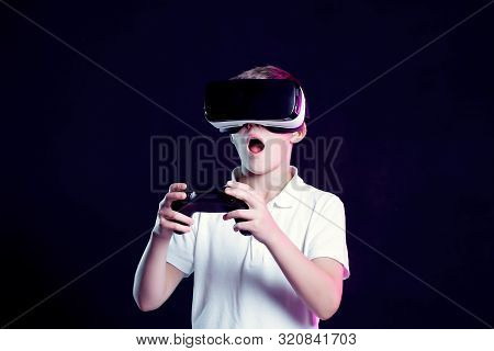 Excited Kid In White T-shirt And Virtual Reality Headset Standing Bending Forward Playing With Joyst