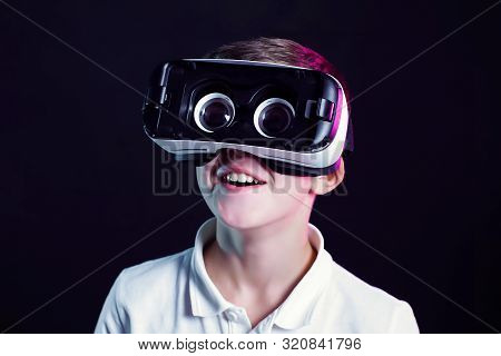 Side View Of Excited Kid In White T-shirt And Virtual Reality Headset Standing Bending Forward Playi
