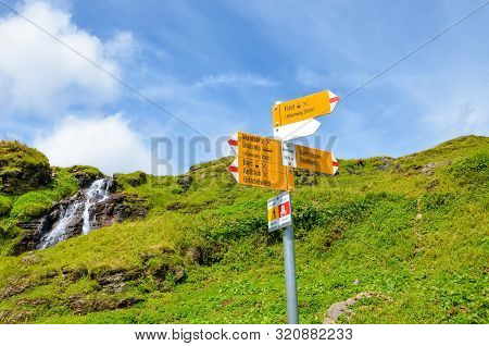 Yellow Tourist Sign In Bachlager, Switzerland Giving Distances And Directions To Hikers In The Swiss