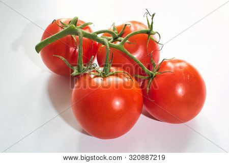 Four Red Tomatoes On A White Background With A Green Rispe.